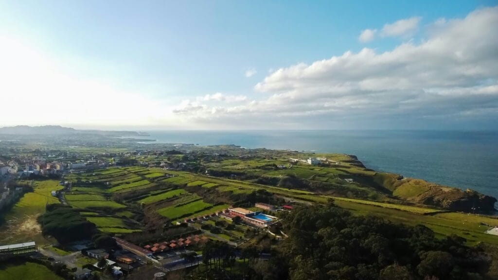 Paisaje costero de Cantabria con campos verdes, viviendas y el mar Cantábrico al fondo