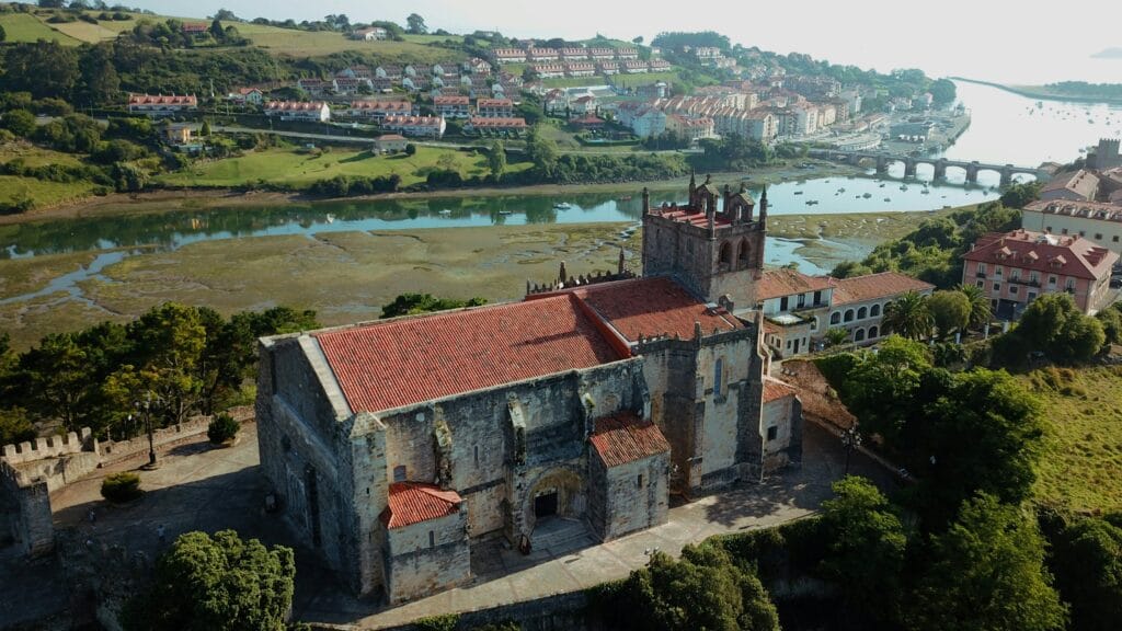 Vista aérea de San Vicente de la Barquera, con su iglesia y ría rodeadas de naturaleza y viviendas, ejemplo de calidad de vida en Cantabria